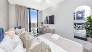 A modern hotel room with a large bed, a desk, a chair, a round table, and a balcony with a view. - Refined City Living with Panoramic Views (Johannesburg)
