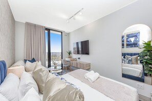 Een moderne hotelkamer met een groot bed, een bureau, een stoel, een ronde tafel en een balkon met uitzicht.