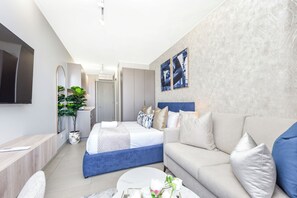 Ein modernes Hotelzimmer mit Bett, Sofa, Fernseher und Kunstwerken an der Wand.