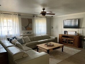 A living room with a sectional sofa, a coffee table, a TV, and a ceiling fan. - Awesome 2-bedroom house with AC in charming KELLER ISD (Fort Worth)