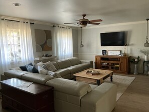 Een woonkamer met een bank, salontafel en een televisie aan de muur.