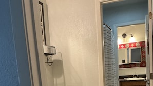 Een badkamer met een wit toilet, een houten wastafelmeubel, een handdoekrek en een douchegordijn.