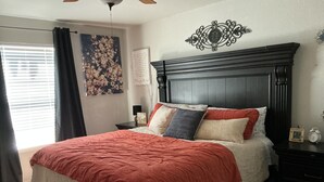 Een slaapkamer met een groot bed, een donker houten hoofdbord en een decoratief wandkunstwerk.