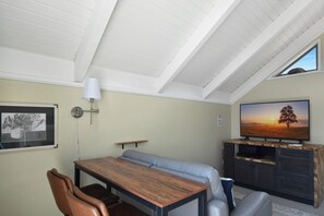 Ein modernes Wohnzimmer mit einem Holzesstisch, einer Ledersofa und einem Fernseher auf einem Holzständer.