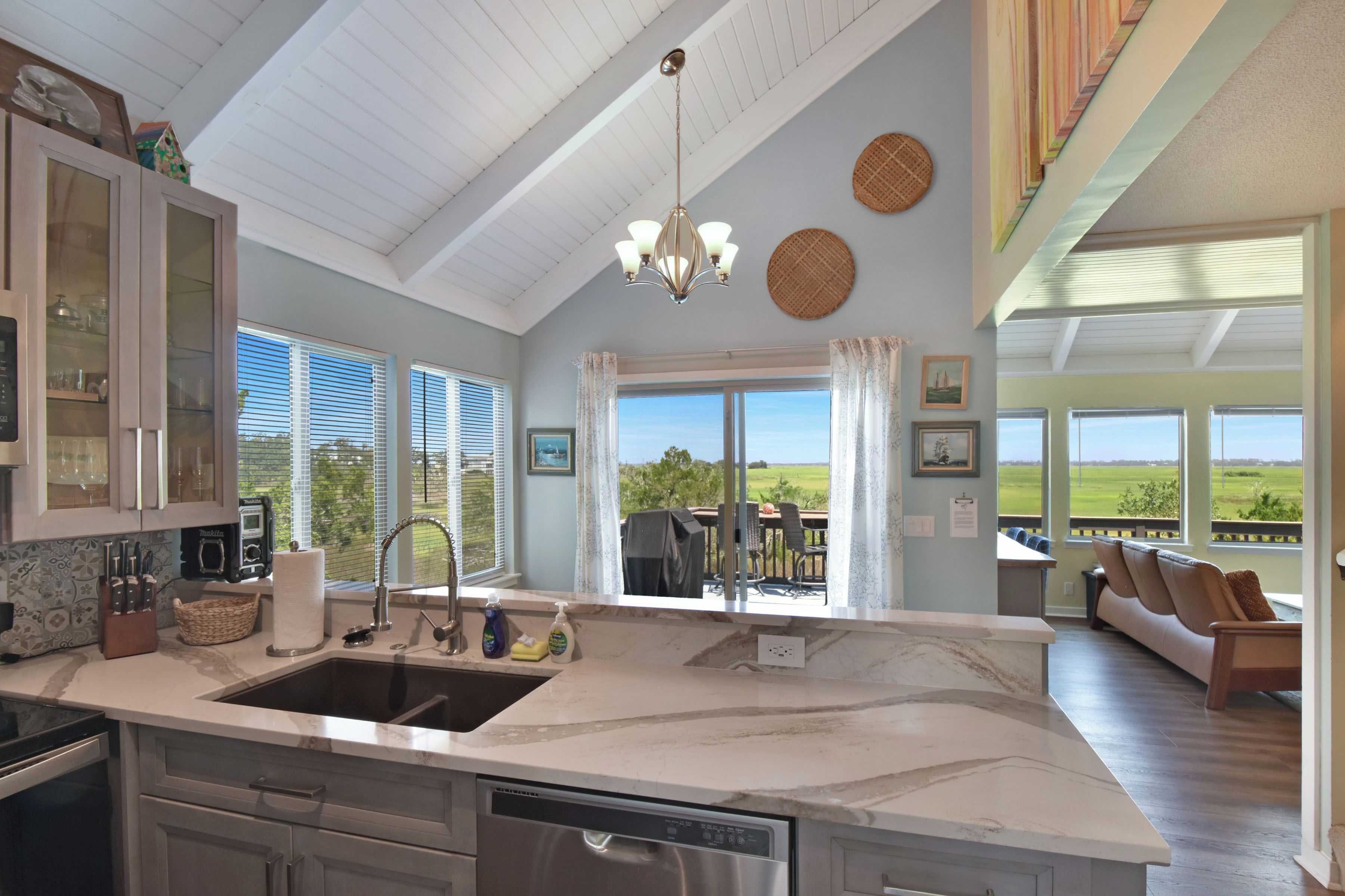 A spacious kitchen with a large island, a dining area with a view, and a living room with a sofa and a table.