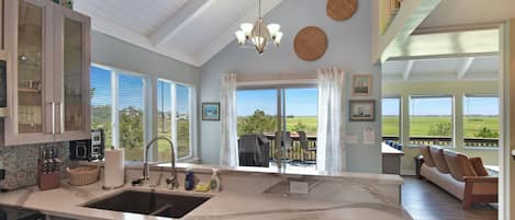 A spacious kitchen with a large island, a dining area with a view, and a living room with a sofa and a table.