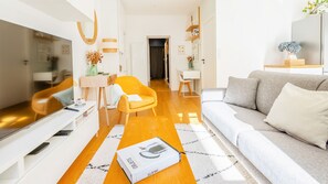 Una sala moderna con un sofá, un sillón y un comedor con una mesa y sillas.