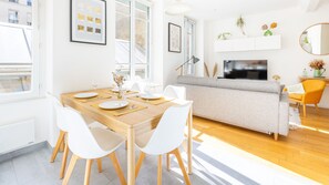 Un comedor moderno con una mesa de madera, sillas blancas y un sofá gris.