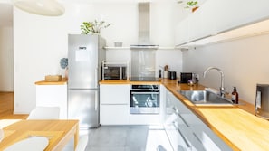 A modern kitchen with stainless steel appliances, wooden countertops, and a built-in oven. - Bonne Nouvelle Home - Appt 2 chambres proche gare (Paris)
