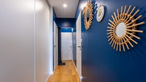 A hallway with a wooden floor, a blue wall, and a door at the end. - Bonne Nouvelle Home - Appt 2 chambres proche gare (Paris)