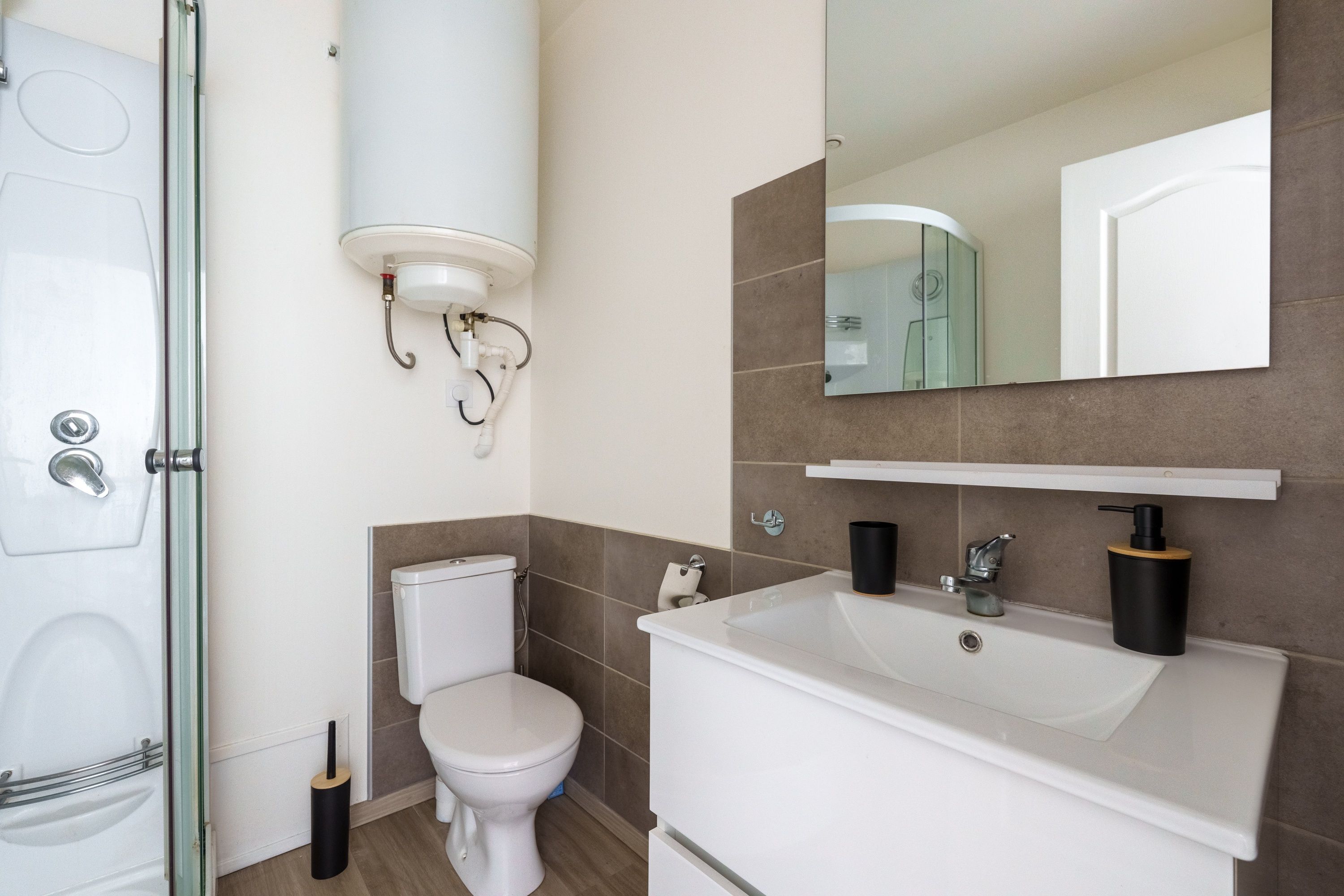 Een moderne badkamer met toilet, wastafel en spiegel.