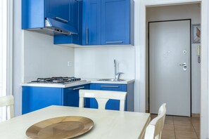 Eine Küche mit blauen Schränken, einem weißen Tisch und einer Tür mit einem Telefon.
