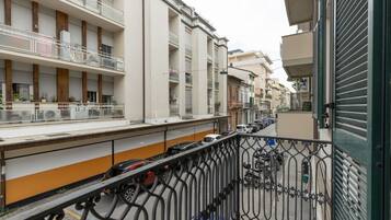 Un edificio residencial con varios balcones, una zona de estacionamiento y una entrada con portón.