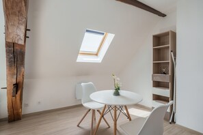Una habitación con tragaluces, una mesa redonda con sillas y una estantería.