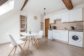 A modern kitchen with white cabinetry, a built-in dishwasher, and a washing machine. - Le 4 Saint-Blaise - Studio spacieux et rénové (Autun)