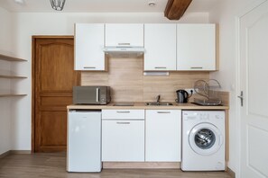 Una cocina compacta con muebles blancos, un microondas integrado, un lavavajillas y una lavadora de carga frontal.