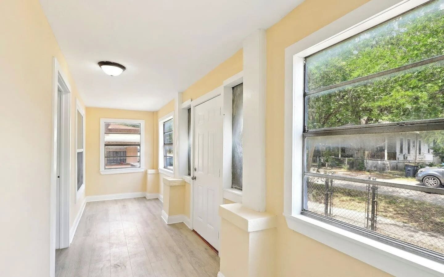 A hallway with a view of a residential area, a door, and a window.