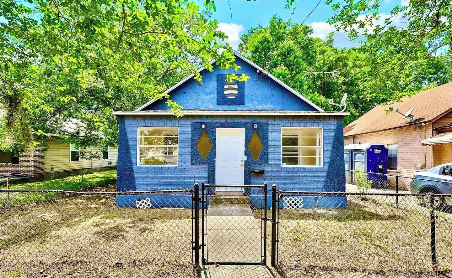 A small, single-story building with a blue exterior, a white door, and a small porch area.