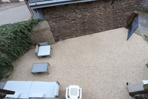Un espace patio agrémenté d’un mur en pierre, d’un portail en métal et de mobilier d’extérieur.