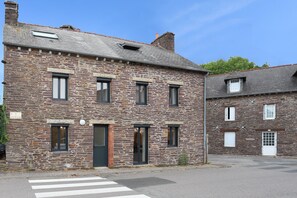 Un bâtiment en pierre à deux étages, doté d’un toit plat, d’une porte et de fenêtres.