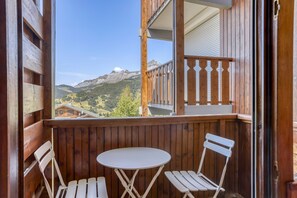 A wooden balcony with a table and chairs, overlooking a mountainous landscape. - L’Écrin du Cernix - 400m du télésiège (Cohennoz)