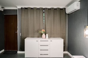 A room with a white cabinet, a vase with flowers, and an air conditioning unit. - Mavie Central Studio 4 (București)