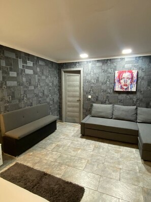 Un salon moderne avec un canapé gris, un banc gris foncé et un sol carrelé de couleur grise.