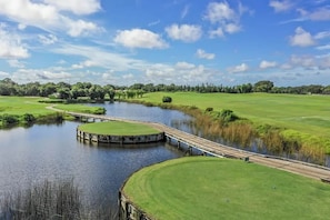 A golf course with a bridge over a body of water, surrounded by greenery and trees. - Casa Delfino (Venice)