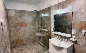 A bathroom with a glass-enclosed shower, a white sink, and a mirror above it.