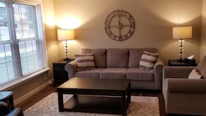 A living room with a sofa set, a coffee table, two lamps, and a wall clock. - Modern Townhome Walking Distance of Downtown (Houghton)