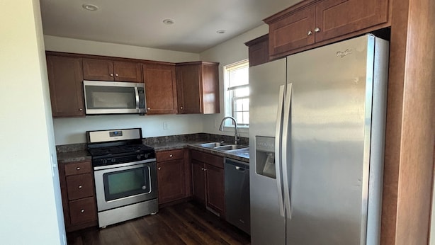 A kitchen with wooden cabinets, stainless steel appliances, and a wooden floor. - Modern Townhome Walking Distance of Downtown (Houghton)