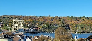 A river with a bridge, buildings, and a hill with trees.