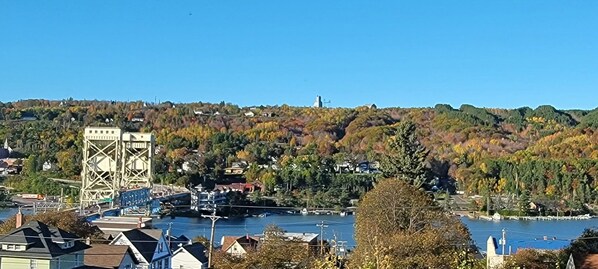 A river with a bridge, buildings, and a hill with trees. - Modern Townhome Walking Distance of Downtown (Houghton)