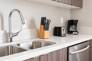 Una cucina con un lavello in acciaio inox a due scomparti, un portachiodi, un tostapane e una macchina da caffè.