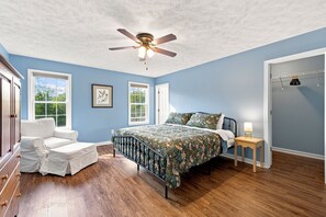 A bedroom with a bed, a chair, a bedside table, a ceiling fan, and a window. - Staunton Stay, Historic Charm & Modern Comfort (Staunton)