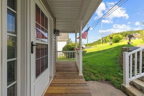 Un portico in legno con ringhiera bianca, una bandiera americana e una cassetta delle lettere.