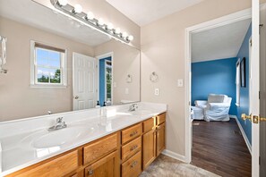 Un bagno con doppio lavabo, uno specchio grande e una cabina armadio.