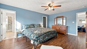 Une chambre à coucher avec un lit, une commode et un ventilateur de plafond.