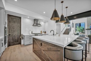A modern kitchen with a central island, stainless steel appliances, and pendant lighting. - Modern Mountain Luxury Lodge! Golf Access & Amenities! (Truckee)