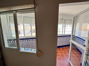 Ein Zimmer mit einer Schiebeglasdoor zu einem Balkon mit gemusterten Fliesen.
