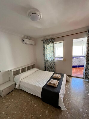 Ein Schlafzimmer mit einem Bett, einem Nachttisch, einem Fenster mit Vorhängen und einer Deckenleuchte.