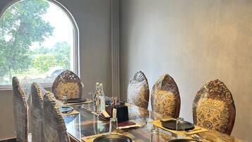 A dining room with a large table, chairs, a chandelier, and a view through a window.