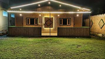 Una casa con porche delantero, dos puertas y un patio cercado de noche.