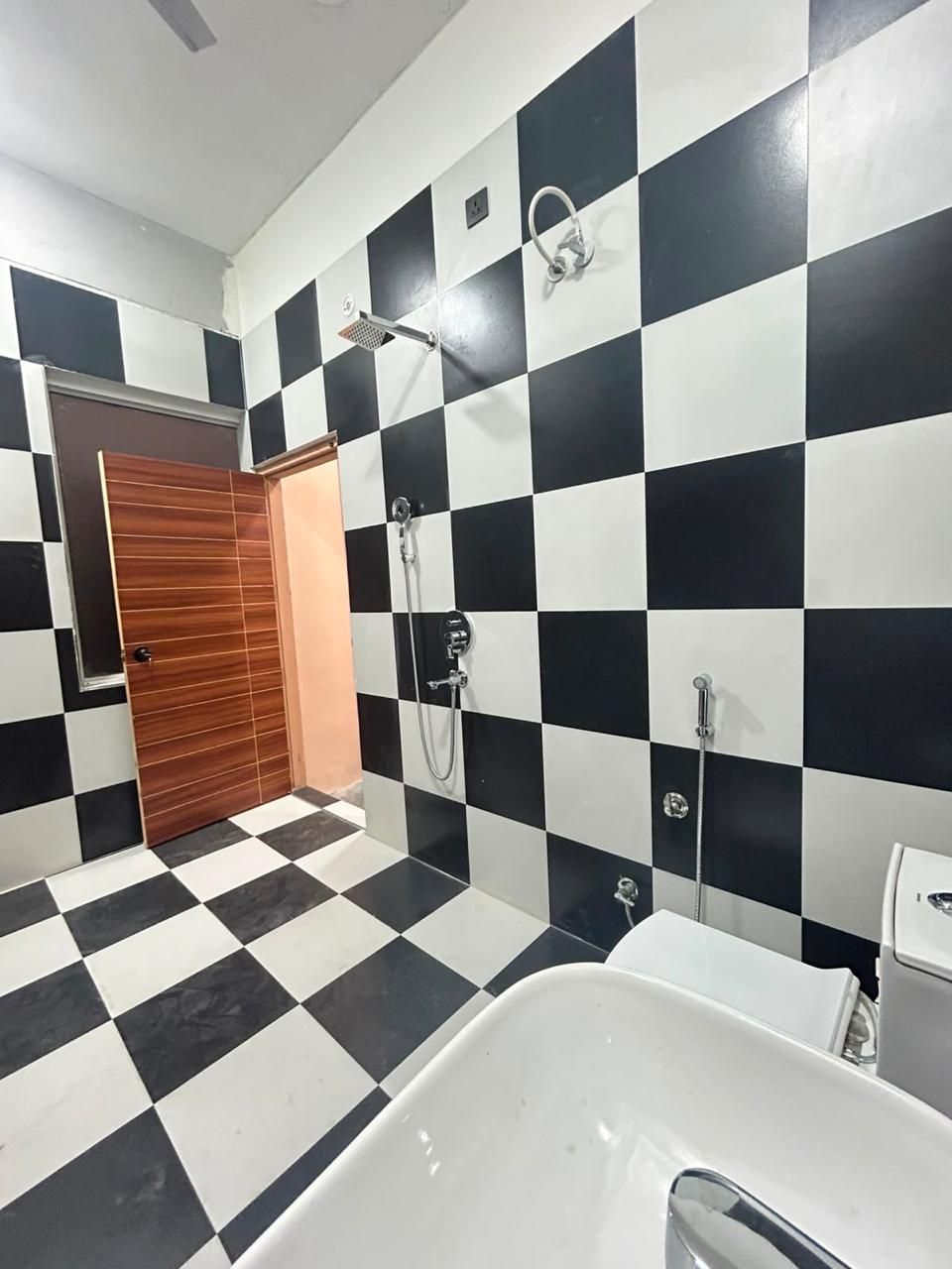A bathroom with a checkered floor, a white bathtub, and a shower with a handheld showerhead.