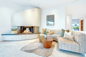 Un salon moderne avec une cheminée, un canapé, une table basse et un tapis à motifs.