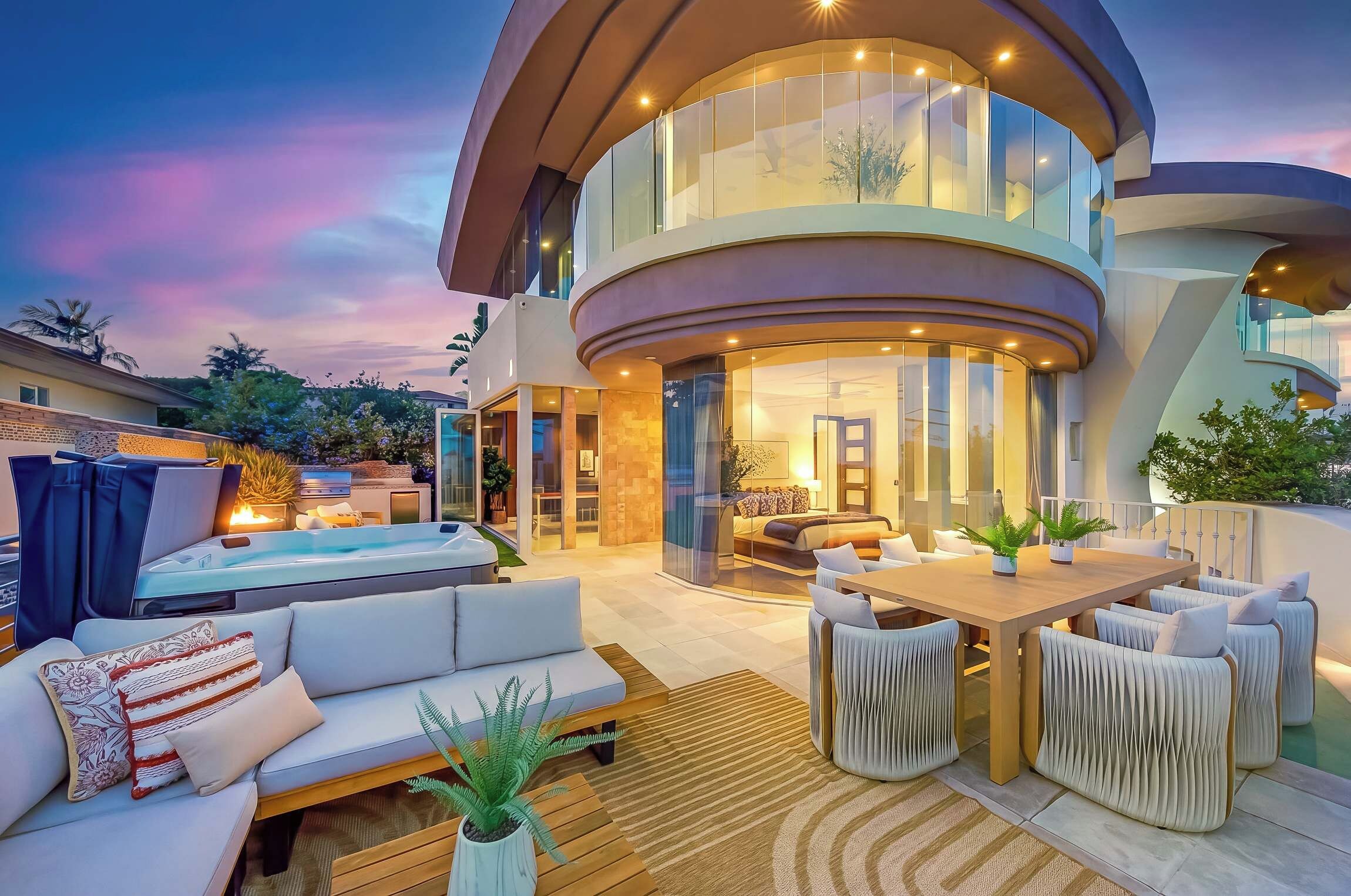Une maison moderne à plusieurs niveaux, dotée d’une façade incurvée, d’une piscine et d’un espace salon extérieur.
