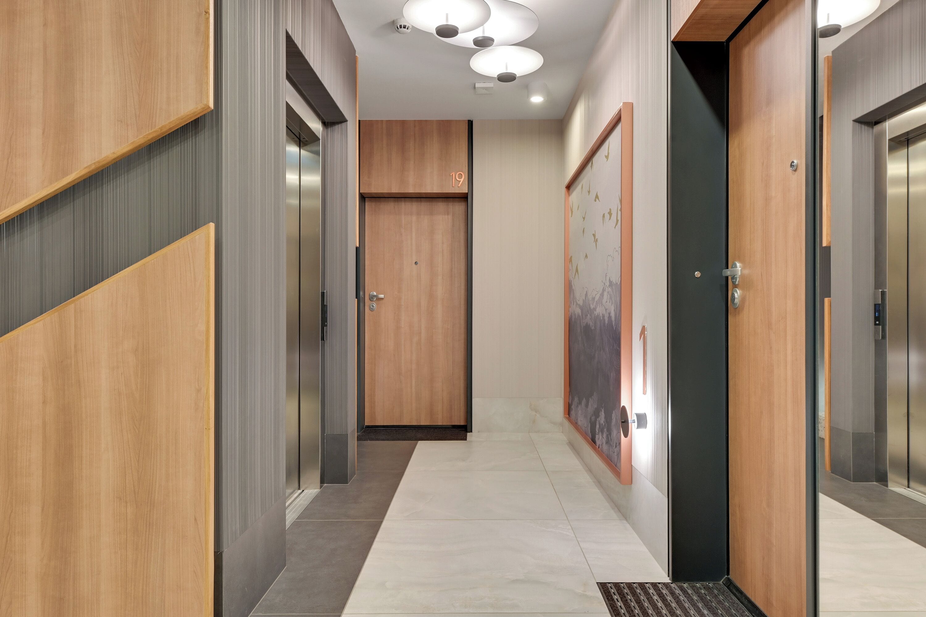A modern hallway with wooden paneling, a door marked with the number 19, and a wall-mounted artwork.