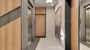 A modern hallway with wooden paneling, a door marked with the number 19, and a wall-mounted artwork.