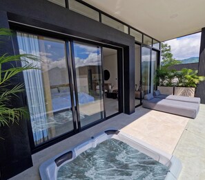 A modern outdoor area with a hot tub, seating, and a view of the landscape.