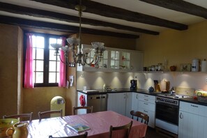 Una cocina con vigas de madera, un candelabro y una mesa de comedor lista para dos comensales.